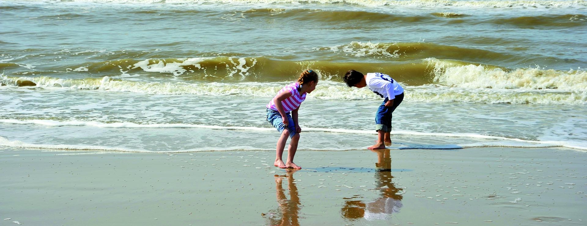 Twee kinderen spelen met de golven op het strand bij Egmond aan Zee